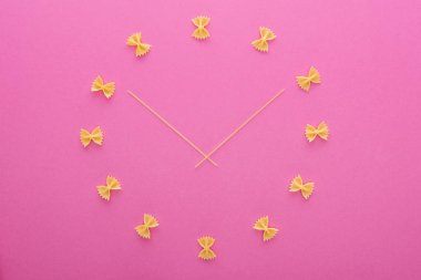 pembe izole orta pişmemiş farfalle makarna ve spagetti ile saat kavramının üst görünümü