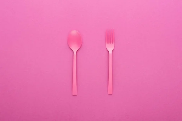 ピンクのプラスチックスプーンとフォークをピンクで分離 — ストック写真