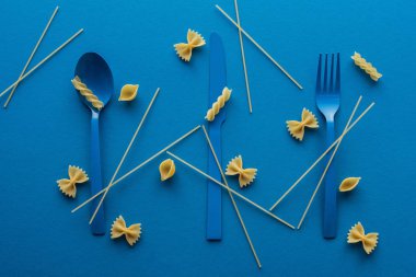 etrafında pişmemiş spagetti ve mavi arka plan makarna farklı türde mavi plastik çatal