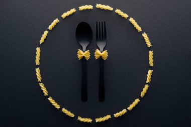 rotini makarna daire içinde kaşık ve çatal üzerinde farfalle makarna üst görünümü 