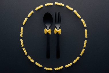 top view of farfalle pasta on spoon and fork in circle from rotini pasta  clipart