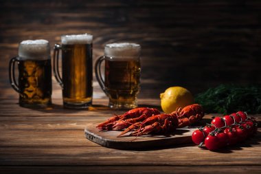 ahşap yüzeyüzerinde bira ile kırmızı ıstakoz, domates, dereotu, limon ve gözlük seçici odak