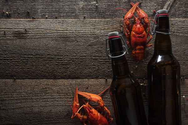 top view of red lobsters and bottles with beer on wooden surface