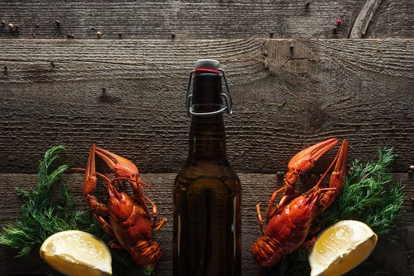stock image top view of red lobsters, dill, lemon slices and bottle with beer on wooden surface