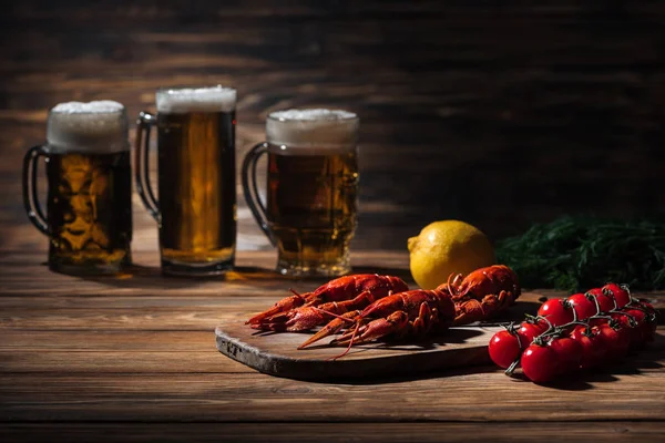 Selective focus of red lobsters, tomatoes, dill, lemon and glasses with beer on wooden surface — Stock Image Selective Focus Red Lobsters Tomatoes Dill Lemon Glasses Beer Wooden Royalty Free Stock Photos