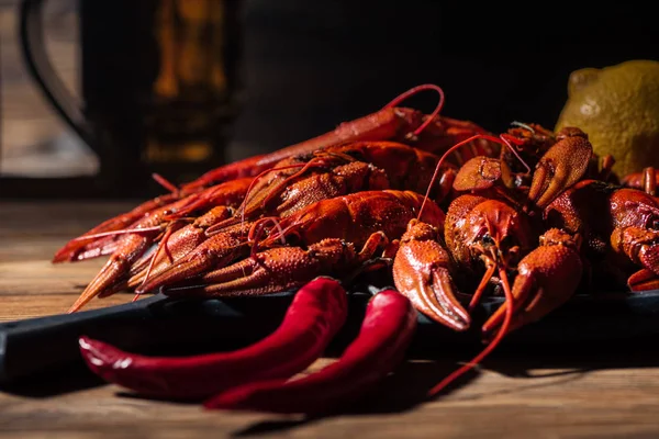 Selective focus of red lobsters, tomatoes, lemon, peppers and glass with beer on wooden surface — Stock Image Selective Focus Red Lobsters Tomatoes Lemon Peppers Glass Beer Wooden Stock Picture