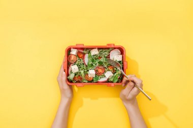 elinde salata ile çatal ve öğle yemeği kutusu tutan kadın kırpılmış görünümü
