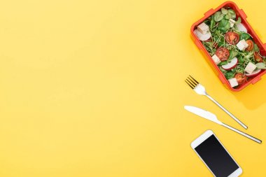 çatal, bıçak ve akıllı telefon yakın salata ile öğle yemeği kutusunun üst görünümü