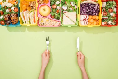 cropped view of woman holding fork and knife near lunch boxes with food clipart
