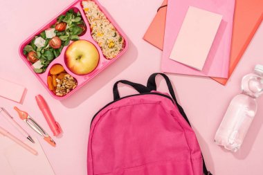 sırt çantası üst görünümü, pembe arka plan üzerinde gıda ve kırtasiye ile öğle yemeği kutusu