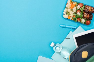 klasörler, kırtasiye, su şişesi, dijital tablet ve öğle yemeği kutusu ile sırt çantası üst görünümü