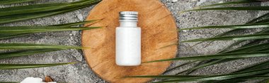top view of coconut beauty product in bottle on wooden board near palm leaves, panoramic shot clipart