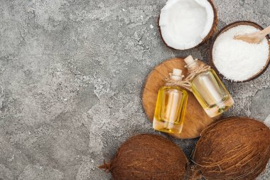 kopya alanı ile gri dokulu arka plan üzerinde ahşap tahta üzerinde şişelerde hindistan cevizi yağı üst görünümü
