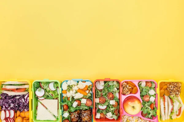 コピースペース付きの黄色の背景に食べ物を持つ弁当箱のトップビュー — ストック写真