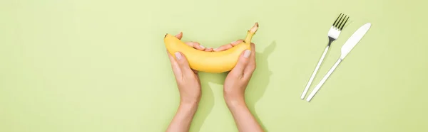 Vista Recortada Mujer Sosteniendo Plátano Las Manos Cerca Tenedor Cuchillo — Foto de Stock
