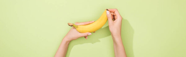 cropped view of woman holding banana in hands