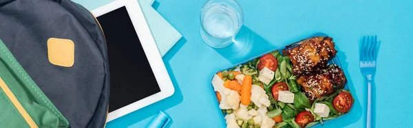 panoramic shot of backpack with folders, digital tablet, stationery near glass of water and lunch box