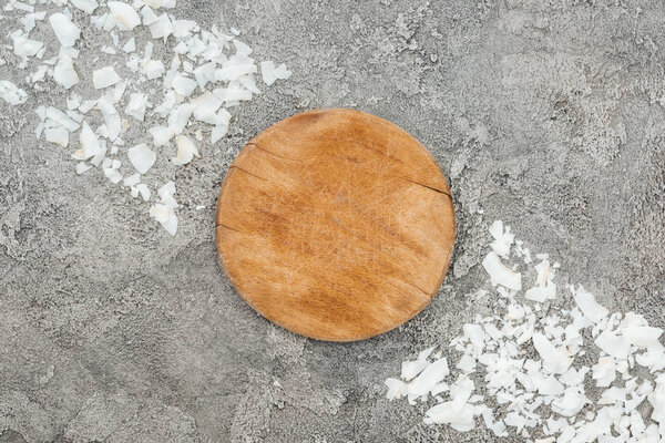 top view of coconut shavings near wooden board on grey textured background