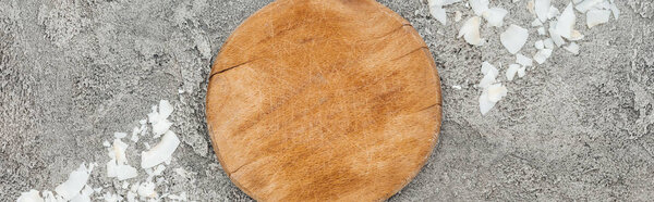 top view of coconut shavings near wooden board on grey textured background, panoramic shot