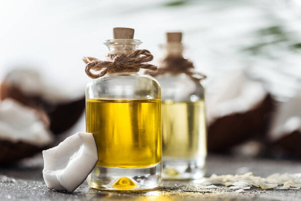 selective focus of bottles with coconut oil near coconut piece and shavings