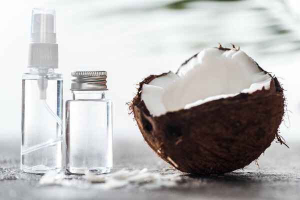 selective focus of bottles with coconut water near cracked coconut and coconut shavings