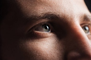 close up view of adult man looking away in darkness clipart