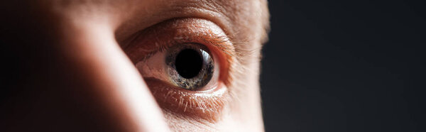 close up view of human eye looking away isolated on black, panoramic shot