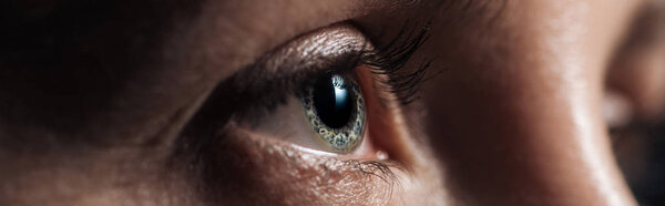 close up view of human eye looking away in dark, panoramic shot