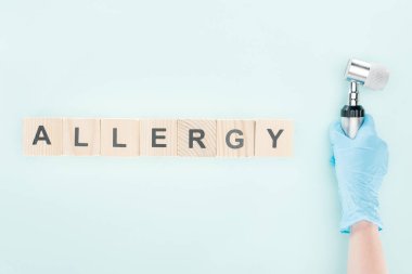 mavi izole alerji yazıtile ahşap bloklar yakınında dermatoskop tutan doktor kırpılmış görünümü