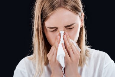 woman blowing her nose in napkin isolated on black clipart