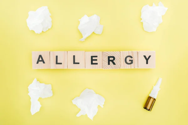 黄色で分離されたナプキンと鼻スプレーの近くに単語アレルギーを持つ木製のブロックのトップビュー — ストック写真