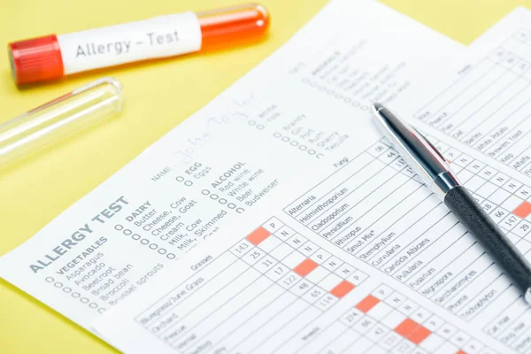 black pen on allergy test results near test tubes with allergy test inscription isolated on yellow