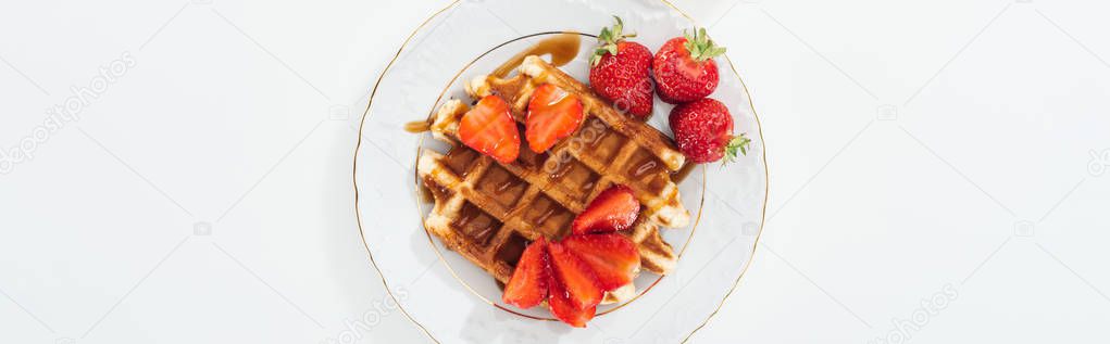 top view of plate with waffle and strawberries on white