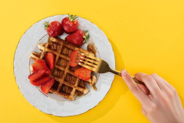 sarı üzerinde waffle ile tabaktan çilek alarak kadın kırpılmış görünümü