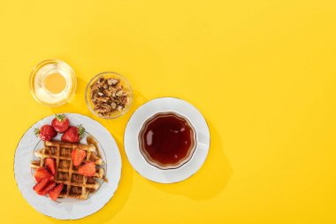 sarı üzerinde waffle, çilek, bal ve fındık üst görünümü