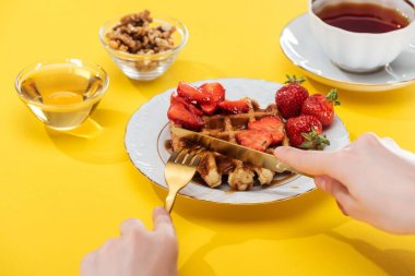 sarı arka plan üzerinde çay ile kase ve fincan yakın tabakta waffle kesme kadın kırpılmış görünümü