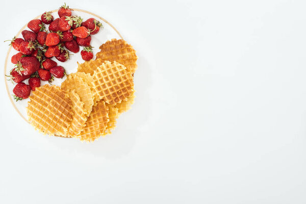 top view of a lot of waffles and strawberries on plate on white