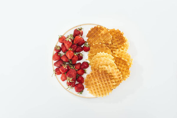 top view of big plate with strawberries and waffles on white 