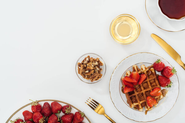 top view of strawberries on plate near bowls on white