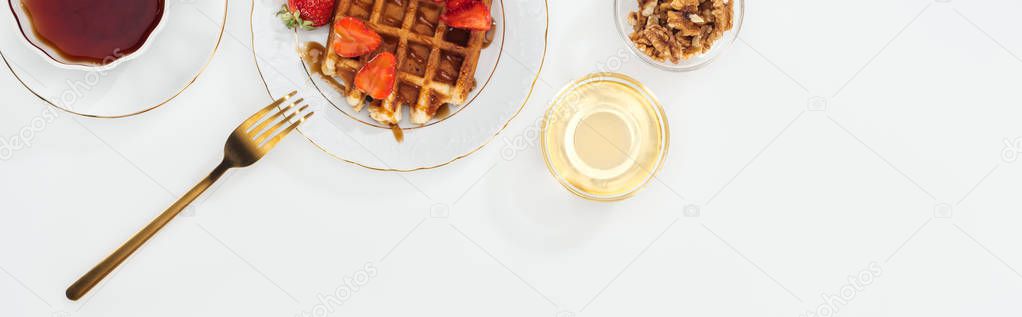 panoramic shot of bowls with nuts and honey near tea and plate with waffles on white