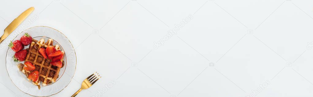 panoramic shot of plate with tasty waffles near fork and knife isolated on white