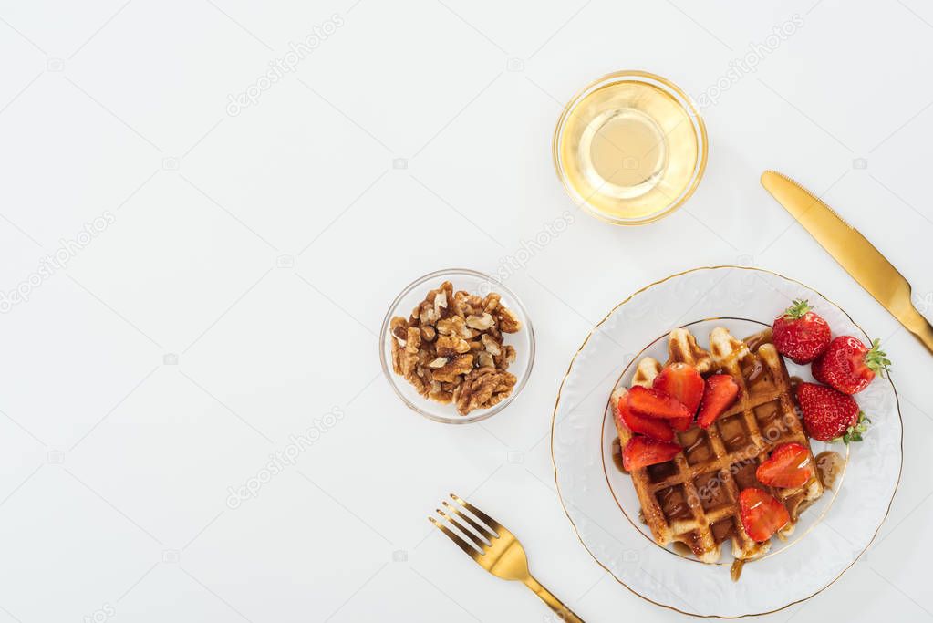 flat lay with crispy waffles and strawberries on plate near bowls on white