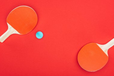 top view of blue ping pong ball near rackets isolated on red  clipart