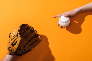 cropped view of man in brown baseball glove near woman holding softball on yellow  clipart