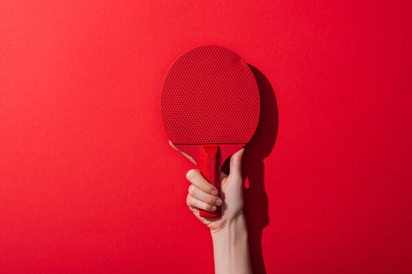 cropped view of woman holding ping pong racket on red 