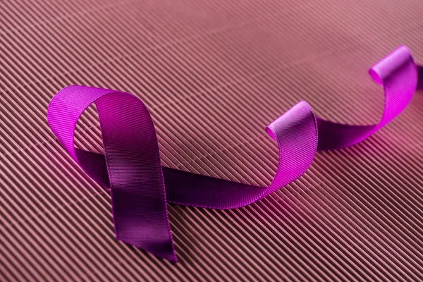 purple ribbon on pink texture background in shadow