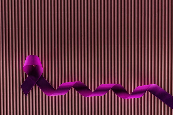 top view of purple ribbon on pink texture background in shadow