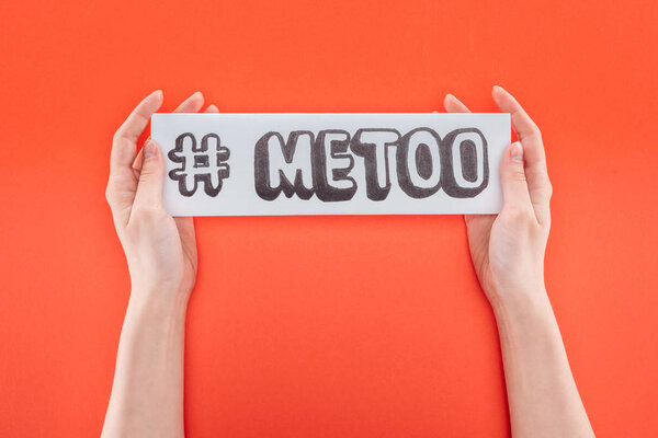 cropped view of woman holding with both hands paper with hashtag me too isolated on orange