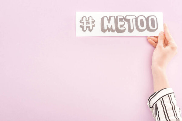 cropped view of woman holding paper with hashtag me too on light pink background