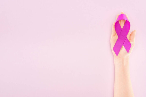 cropped view of purple ribbon on hand of woman isolated on pink